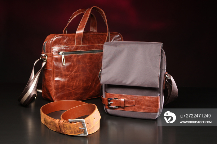 Leather goods. Two bags and a belt on a dark background. Two bags on table. Concept - production of bags from natural materials. Leather briefcase next to backpack. Manufacture of leather goods