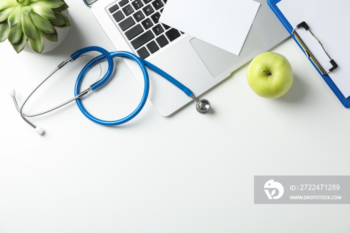 Stethoscope, apple, laptop and plant on white background, top view. Doctor workplace