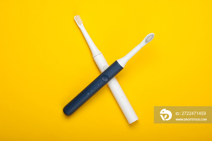 Two Modern electric toothbrushes on yellow background. Top view. Teeth care. Minimalism