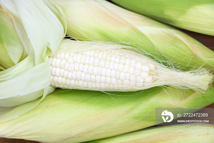 Close up isolated raw white corn (peeled can see inside) on brown wood table background