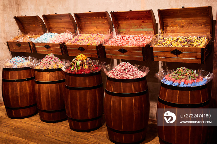 Multicolored gummy candies and marshmallows are sold in the store in wooden barrels and chests