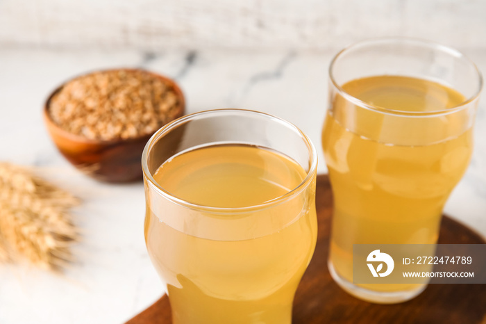 Glasses of fresh kvass on light background