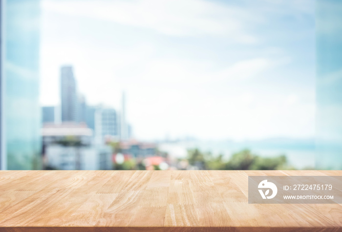 Wood table top on blur window glass,wall background with city view.