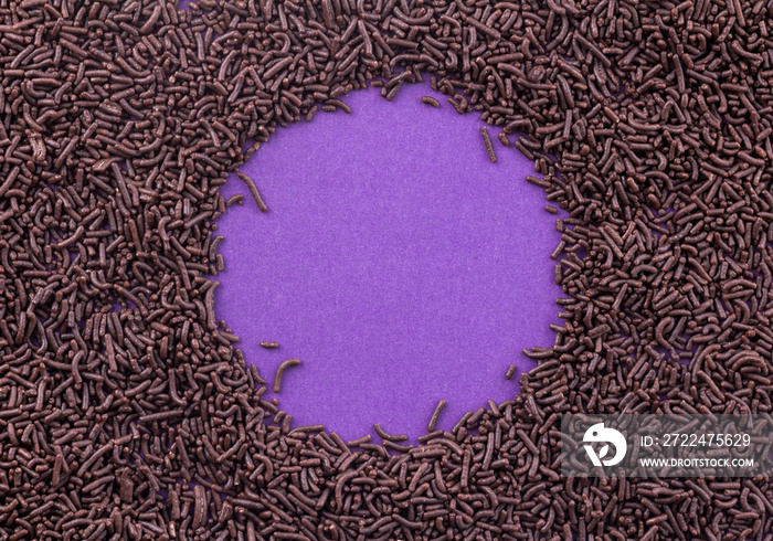 Chocolate sprinkles covering a purple background leaving a circle in centre for text