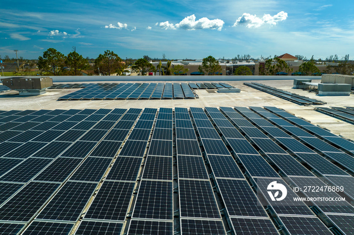 Aerial view of blue photovoltaic solar panels mounted on industrial building roof for producing green ecological electricity. Production of sustainable energy concept