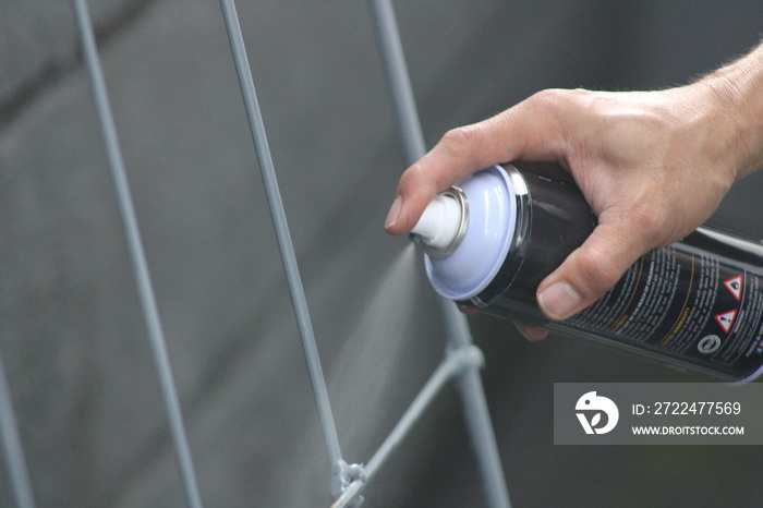 Closeup of man painting a fence with spray paint or aerosol paint