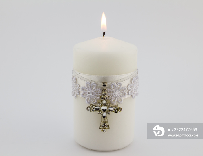 White candle with lace, ribbon and Christian cross pendant isolated on white background