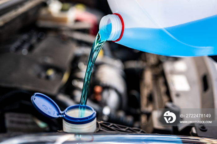 Pouring antifreeze. Filling a windshield washer tank with an antifreeze in winter cold weather...