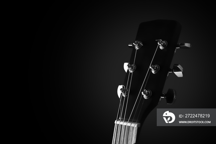 Black and white photo of modern acoustic guitar against dark background, closeup