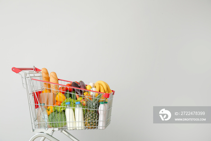 Shopping cart with products near light wall