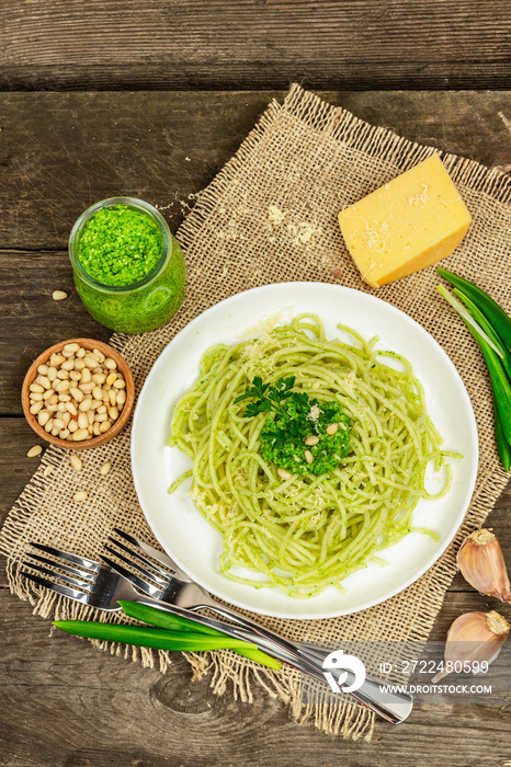 Spaghetti pasta with pesto sauce and fresh ramson leaves. Cutlery, parmesan, pine nuts. Rustic style