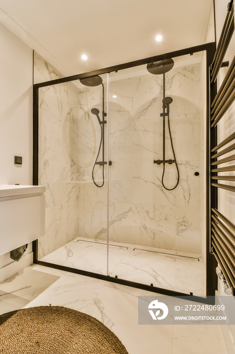 a modern bathroom with marble flooring and black trim on the shower door, along with a round rug in front