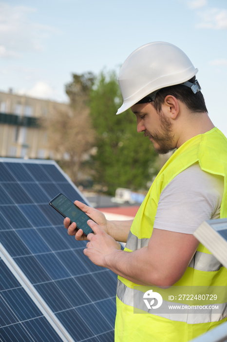 Technician using smartphone app for controlling photovoltaic solar power station. Green eco friendly energy.