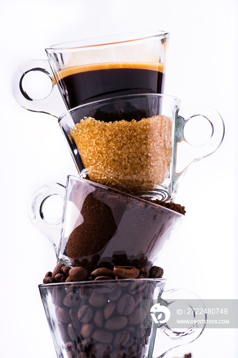 glass cups, in vertical sequence, with coffee beans, ground coffee, brown sugar and a creamy drink. still life