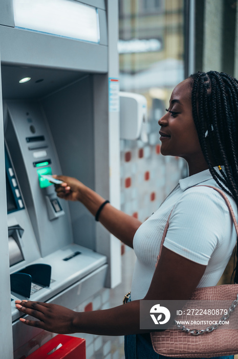 African american woman inserting credit card and withdrawing cash at ATM