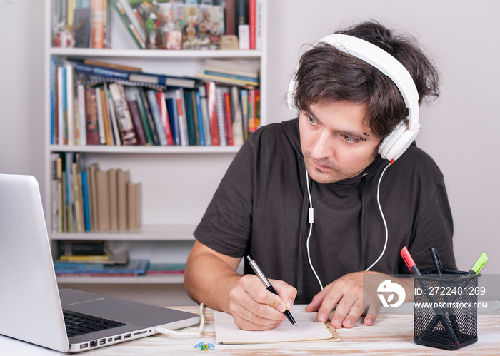 E-Learning. Man with headphones sydying by Laptop