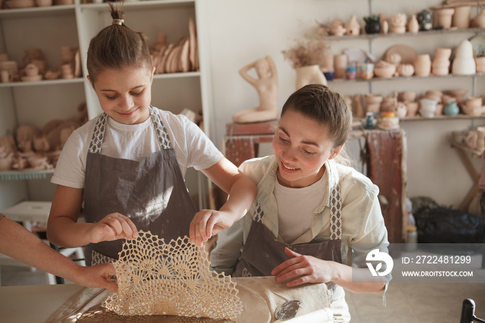 Cheerful young boy and his mom preparing clay to make tableware in pottery class