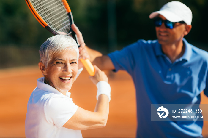 Tennis Instructor Teaching Elderly Woman How to Play Tennis