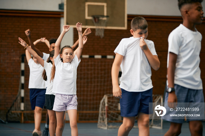 Group of school children exercising during physical education class at school gym.