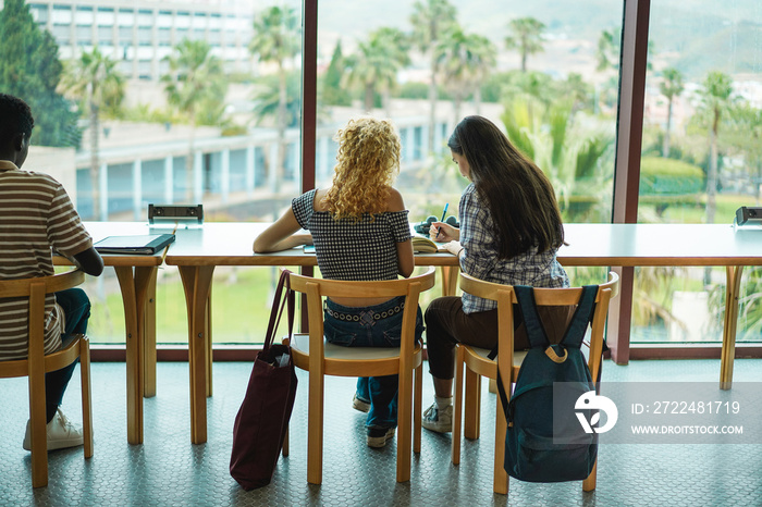 Young students studying inside university library - Focus on girls back