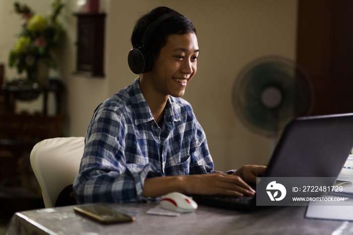 Happy young teenage of Asian boy enjoying with online class chat on laptop camera at home, Night scene.