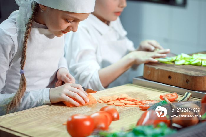 Children grind vegetables in the kitchen.