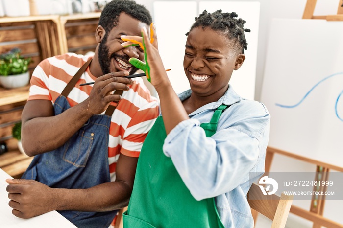 African american painter couple smiling happy painting hands sitting on the table at art studio.