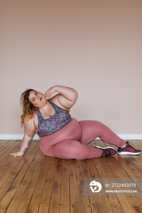 portrait of a plus size woman sitting on floor stretching