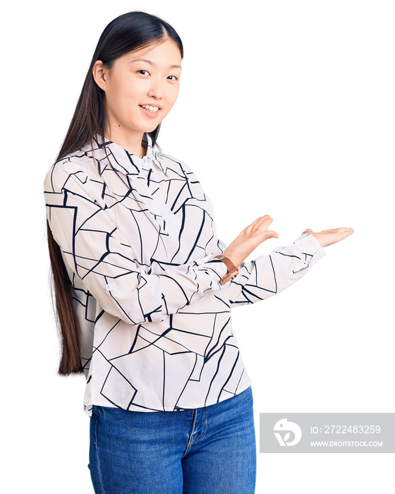 Young beautiful chinese woman wearing casual shirt inviting to enter smiling natural with open hand
