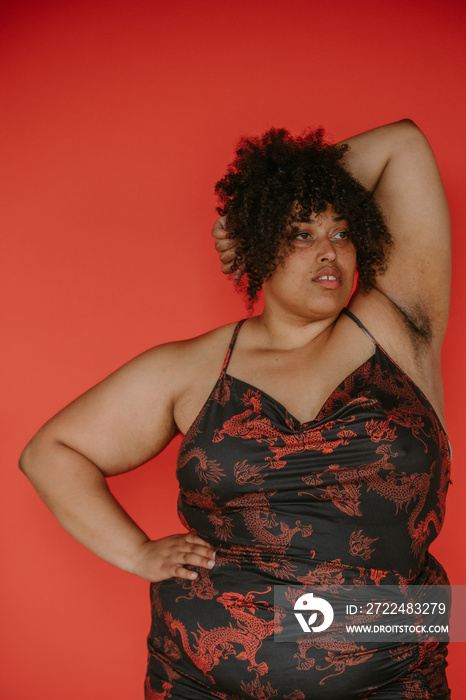 portrait of a plus size afro indigenous person looking away on red backdrop