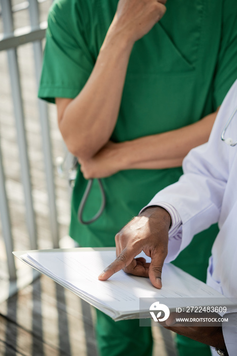 Close-up image of chief physician explaining doctor what information patients need to write in new form