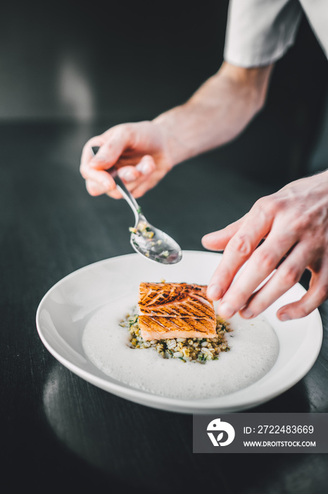 Restaurant chef preparing fish food on dark table. Organic fish food