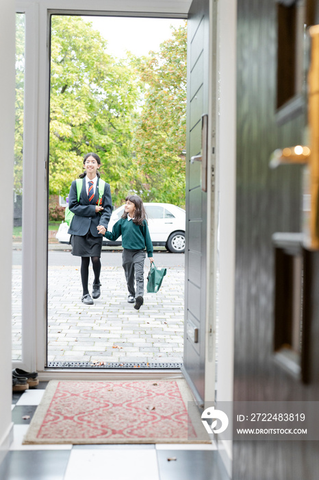 Sisters walking into house after returning from school