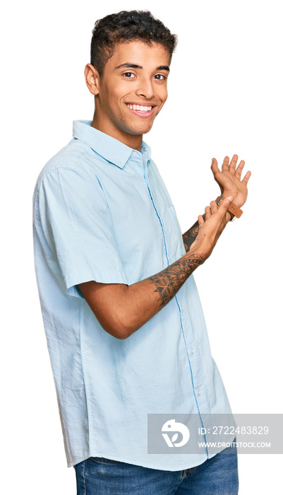Young handsome african american man wearing casual clothes inviting to enter smiling natural with open hand