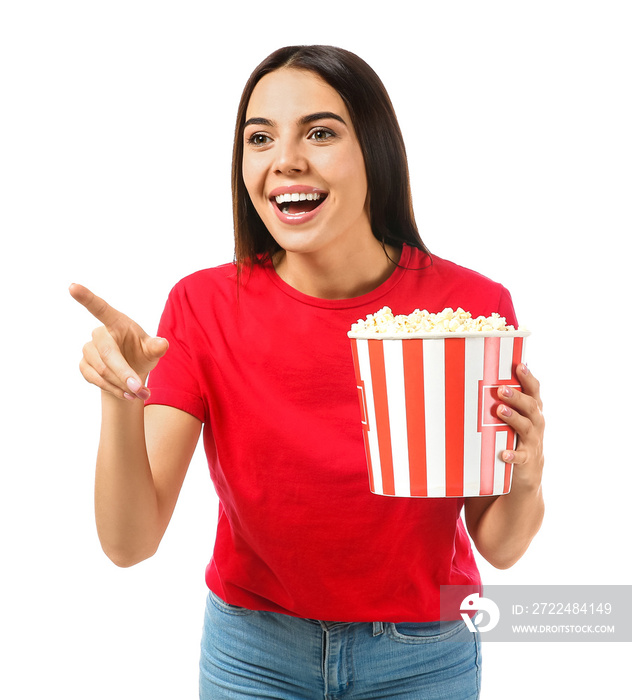 Young woman with popcorn pointing at something on white background