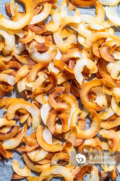 Flat lay of baked coconut chips, top view. Vegan food concept.