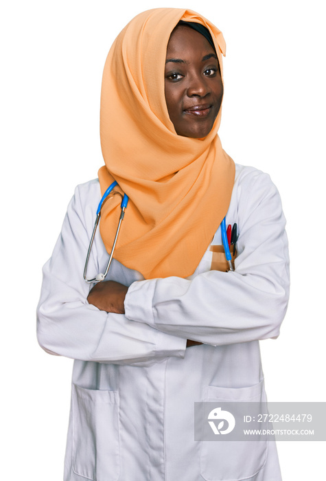 Beautiful african young woman wearing doctor uniform and hijab happy face smiling with crossed arms looking at the camera. positive person.