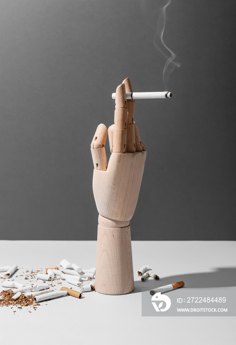 Wooden hand with cigarette on grey background