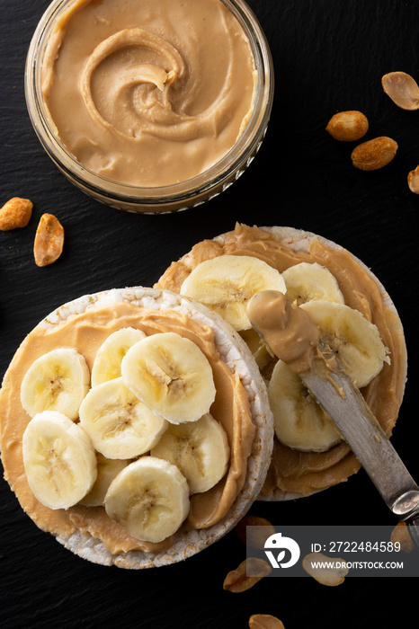 Peanut butter and banana on rice cakes, healthy, dietary food. Black background.
