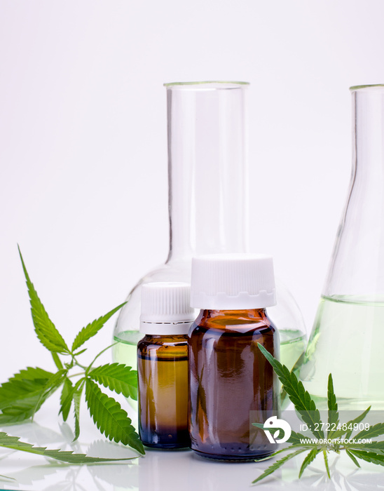 Medical, chemical theme background with cannabis leaves, oil bottle and laboratory glass flasks behind on a white.