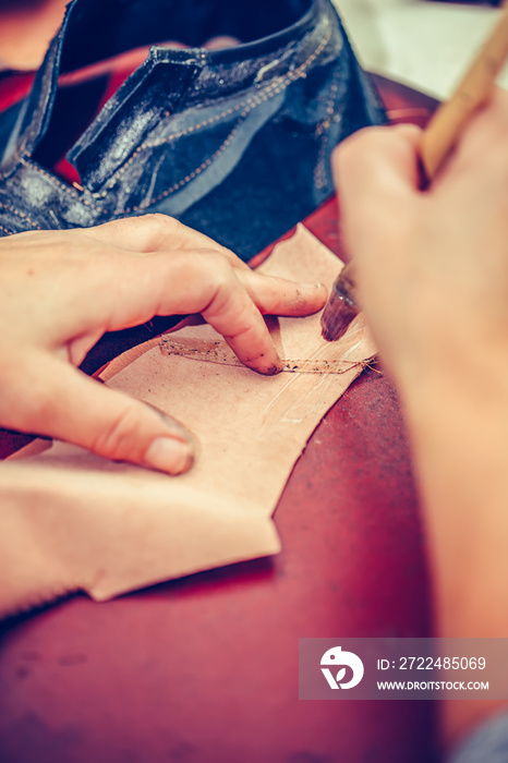 Hands of an experienced worker putting glue on the parts of the shoe.