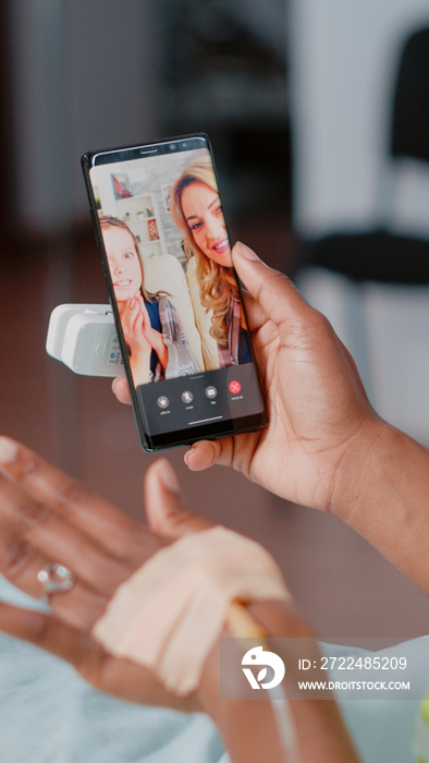 Young woman in bed talking to family on video call, using mobile phone for remote communication. Sick patient using online video conference to talk to relatives in hospital ward.