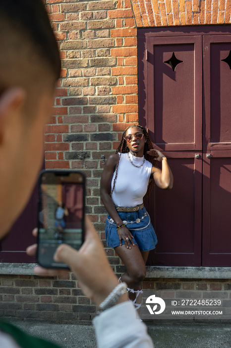 Man photographing fashionable smiling woman with smart phone