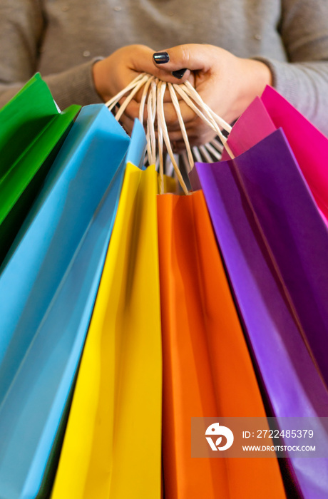 Close-up of a woman’s hands holding colorful shopping bags. Copy space. Shopping Concept