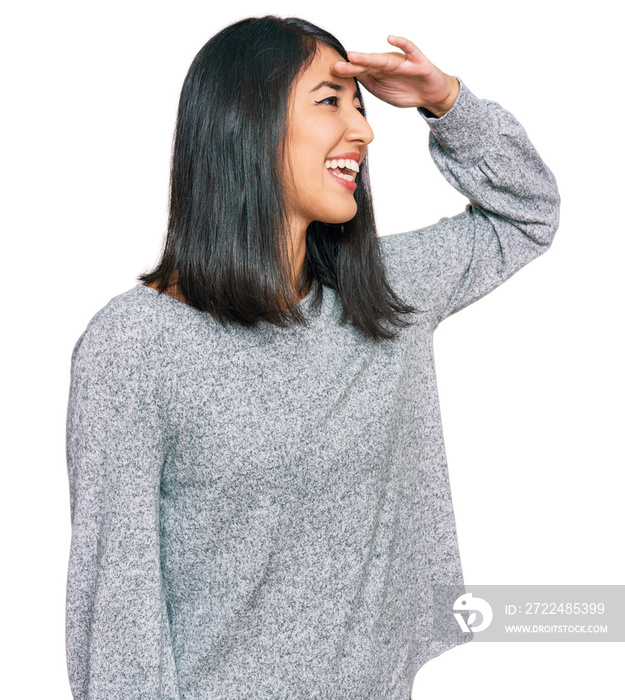 Beautiful asian young woman wearing casual clothes very happy and smiling looking far away with hand over head. searching concept.