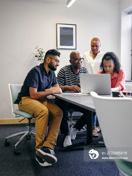 Colleagues looking at laptop during business meeting