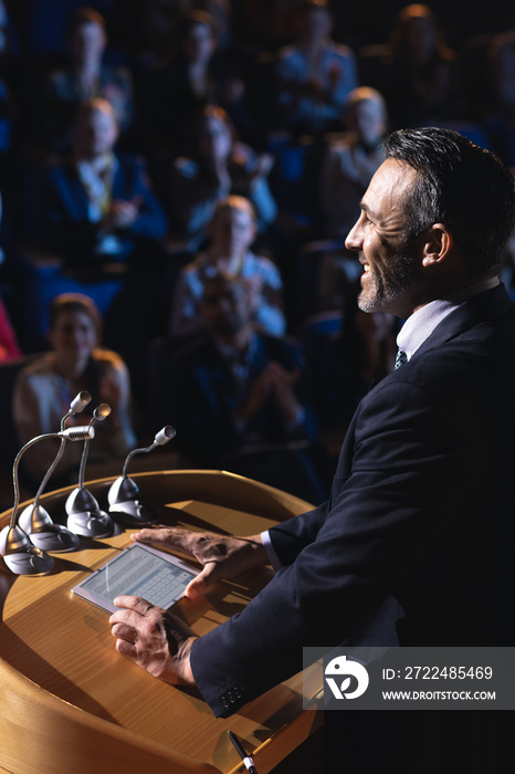 Businessman standing and giving presentation in the auditorium