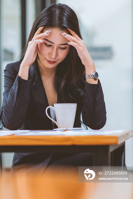 Asian women sitting in a home office With stress and eye strain.Tired businesswoman holding eyeglasses and massaging nose bridge.There are tablets, laptops and coffee.