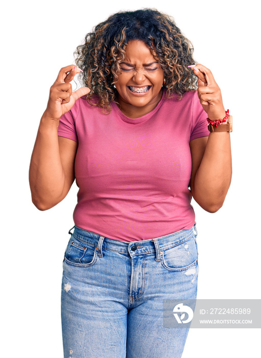 Young african american plus size woman wearing casual clothes gesturing finger crossed smiling with hope and eyes closed. luck and superstitious concept.