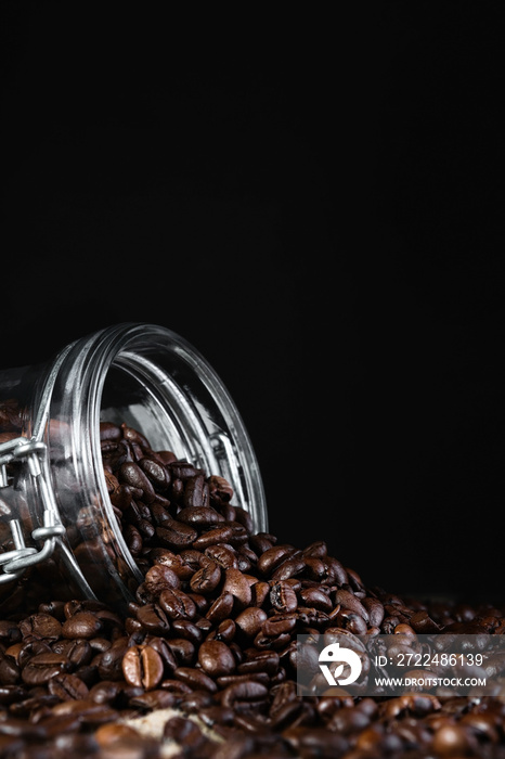 Coffee beans in a glass jar on a black background, close-up, selective focus, vertical frame. Roasting and preparing coffee, vertical frame